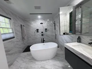 A freestanding tub, walk-in shower and floating vanity in a marble-tiled bathroom