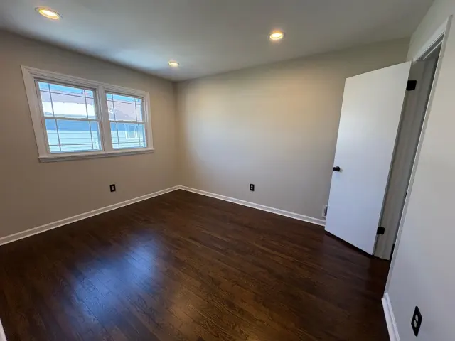 An empty room with dark hardwood floors and a double window