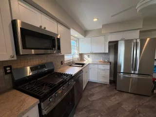 A kitchen with a gas range, stainless appliances and white cabinets