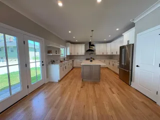 A large kitchen with white cabinets, an island and light hardwood floors