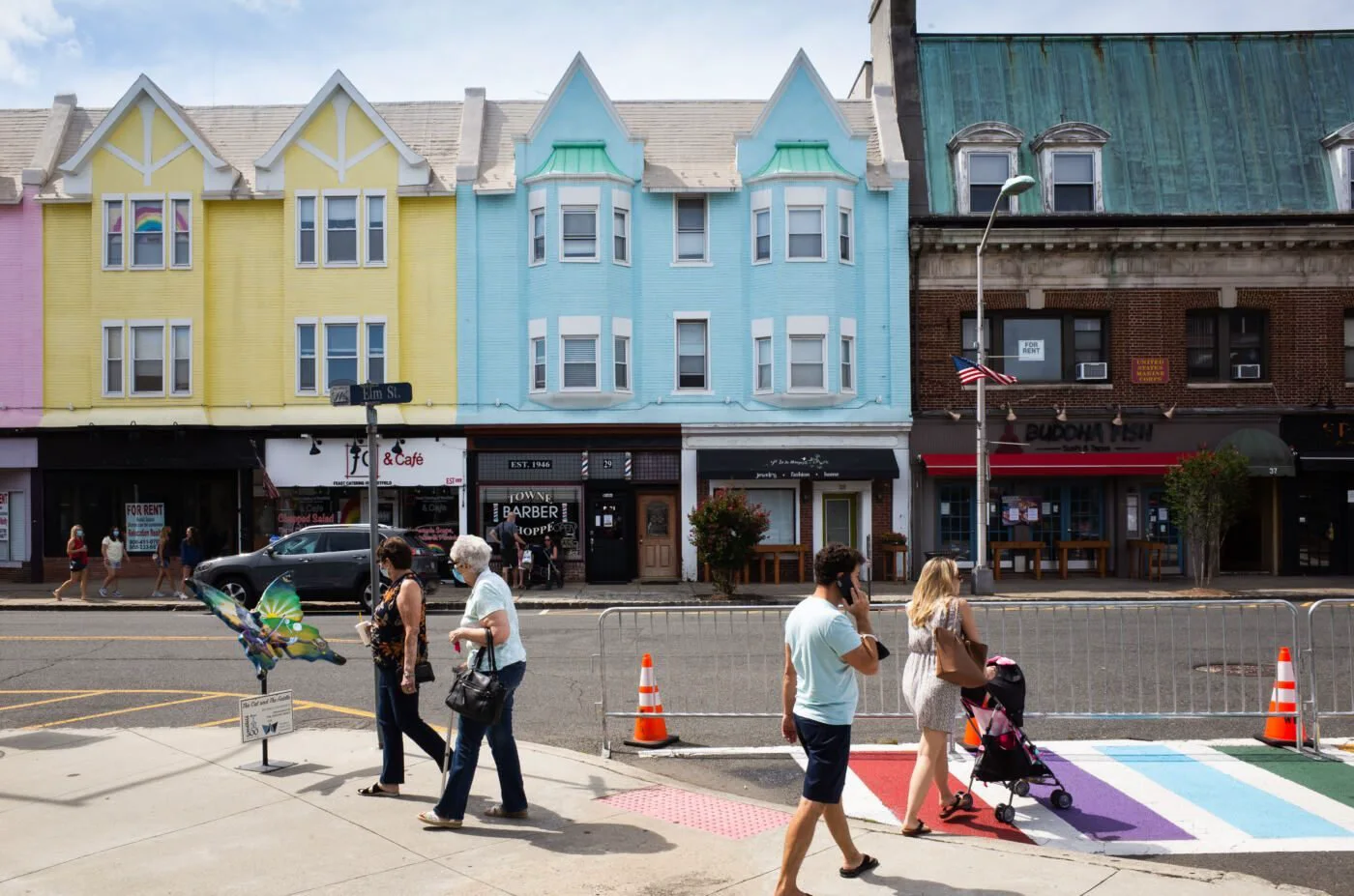Pastel storefronts on Elm Street in downtown Westfield, with people walking past a rainbow crosswalk
