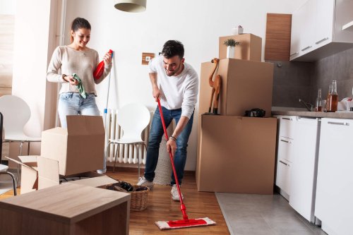 A couple mopping and cleaning among moving boxes