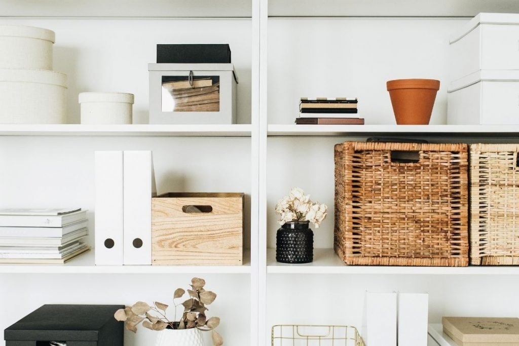 White shelves with storage boxes, wicker baskets and binders