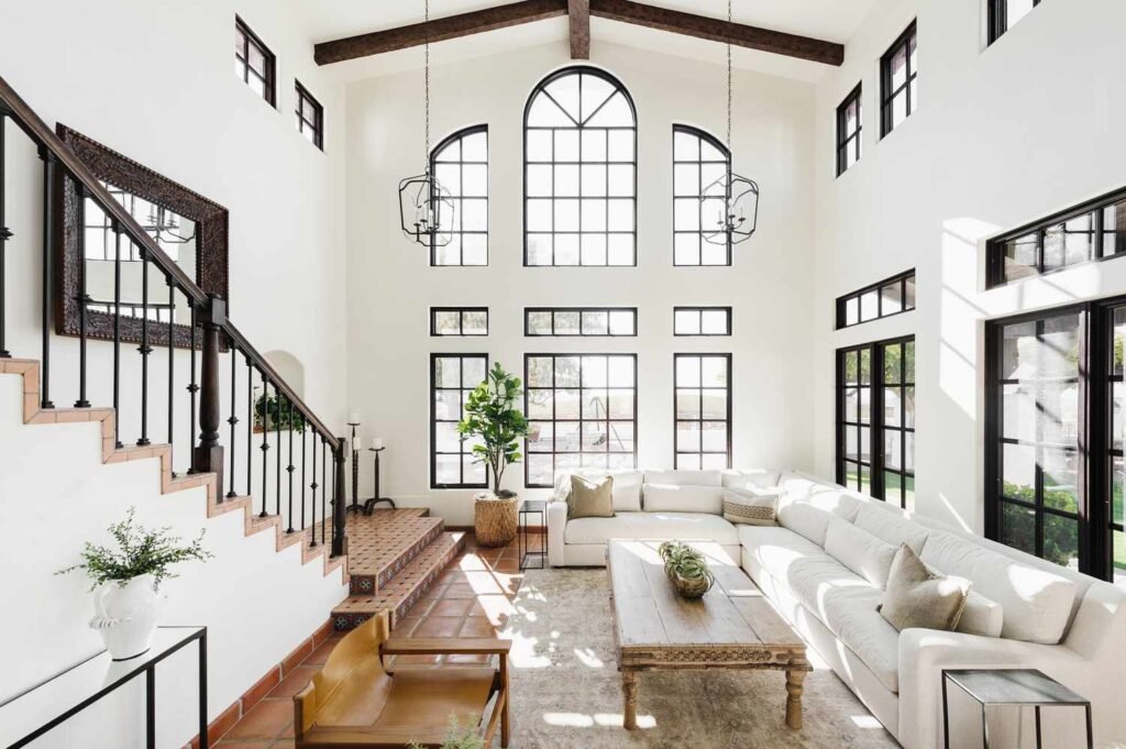 A bright two-story living room with arched windows and a white sofa